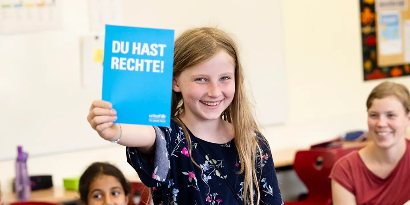 Deutschlandweit besuchen Kinder Kinderrechteschulen Ein Mädchen hält die Kinderrechtskonvention in der Hand